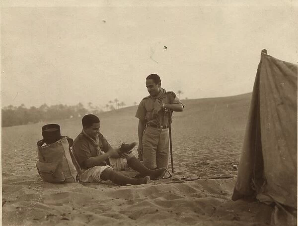 Boy scouts sitting by tent in desert, Egypt