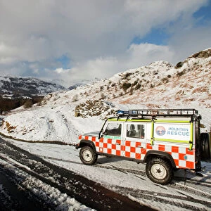 A landrover belonging to the Langdale Ambleside Mountain Rescue Team in winter snow in front of the Langdale Pikes Cumbria