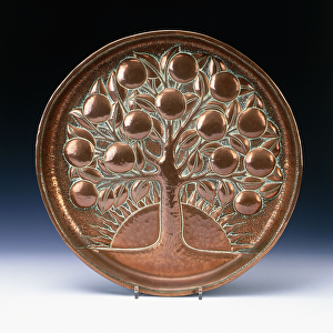 A copper charger hammered in relief with a fruiting tree, before a setting sun