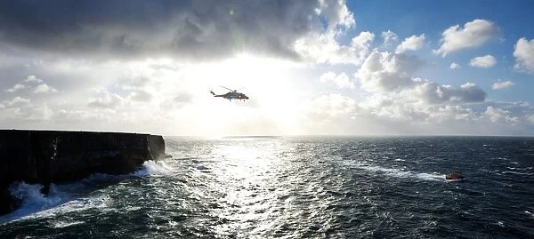 Beyond the dramatic limestone cliffs of the Aran Islands, Irish Coast Guard helicopter Rescue 115 and Severn class David Kirkaldy patrol the heaving Atlantic waters at the entrance to Galway Bay