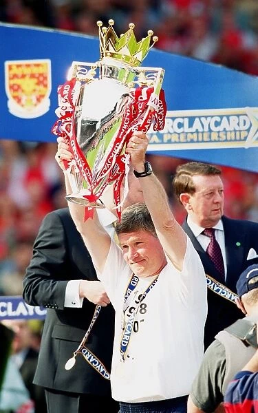 Assistant manager Pat Rice lifts the F. A. Barclaycard Premiership Trophy
