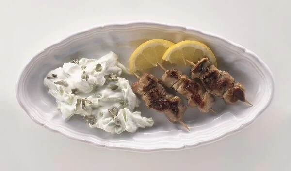 Plate of Souvlaki, Tstatsiki and sliced lemons, served as a meze dish, view from above