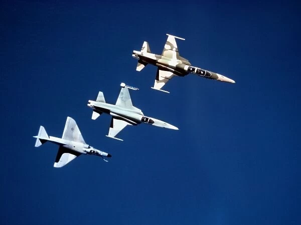 Two F-5 Tiger IIs and an A-4E Skyhawk in flight above the Pacific Ocean