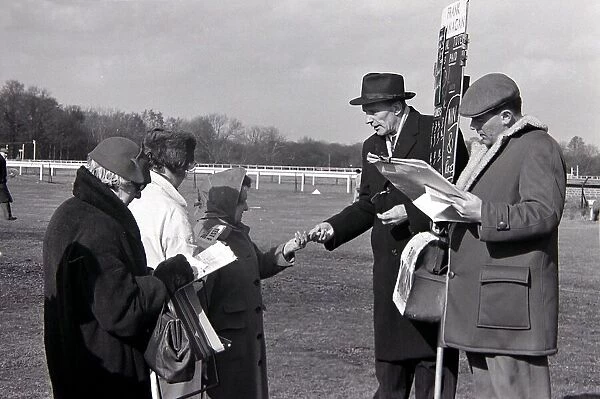 Bookmakers take money from a woman as she places a bet before a race March 1963