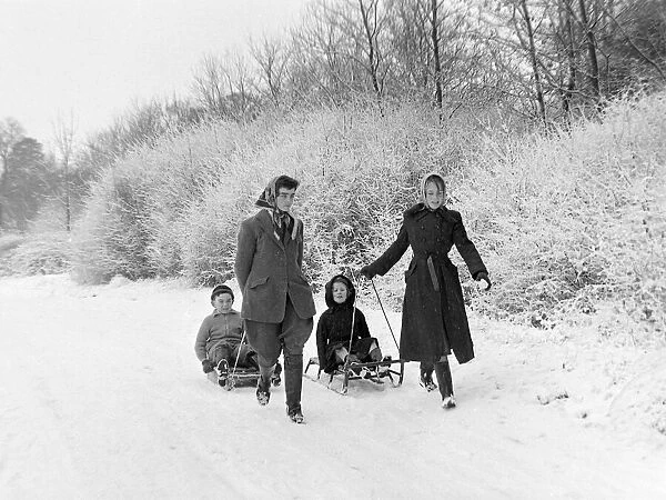 Children sledging in the snow in and around Hadley Wood Hertfordshire - two girls pulling
