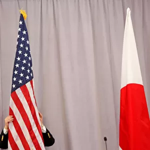 A worker adjusts the U. S. flag before Japanese Prime Minister Shinzo Abe addresses media