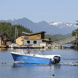 Vancouver Island, Tofino. Motorboat passing in front of floating houses