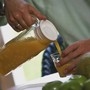 Man pouring orange juice into a glass tumbler