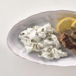 Plate of Souvlaki, Tstatsiki and sliced lemons, served as a meze dish, view from above
