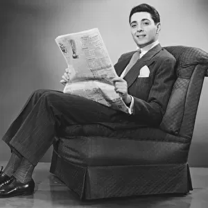 Man sitting on chair, holding newspaper (B&W)
