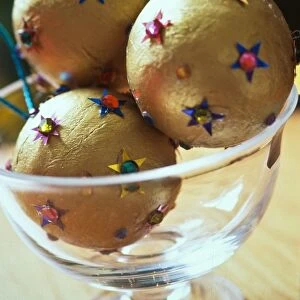 Gold christmas baubles with sequin stars in glass bowl as table centrepiece credit