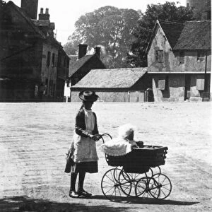 An older sister taking out the baby in a perambulator on a summers day walk taking