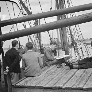 Pupils from the art school sit on the deck of a Thames Barge drawing pictures in