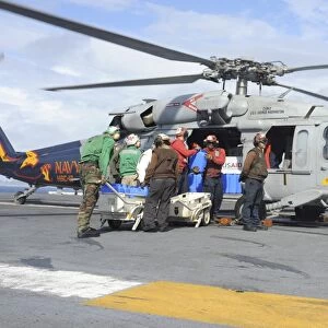 Sailors load fresh water onto an MH-60S Seahawk