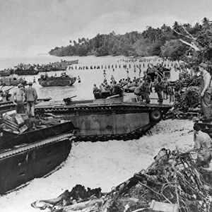 US amphibious tanks line a beach bringing in supplies to American marines who landed