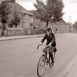 A young schoolboy comes home from school on his bicycle